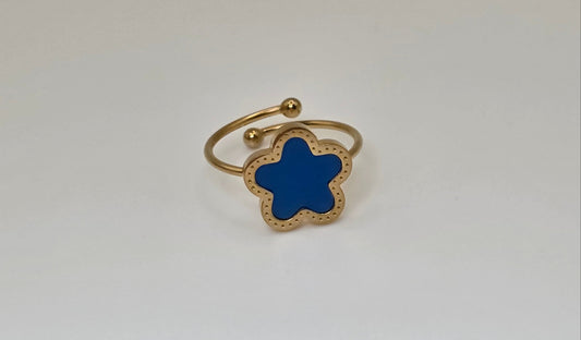 Gold ring with a blue star-shaped stone on a light gray background