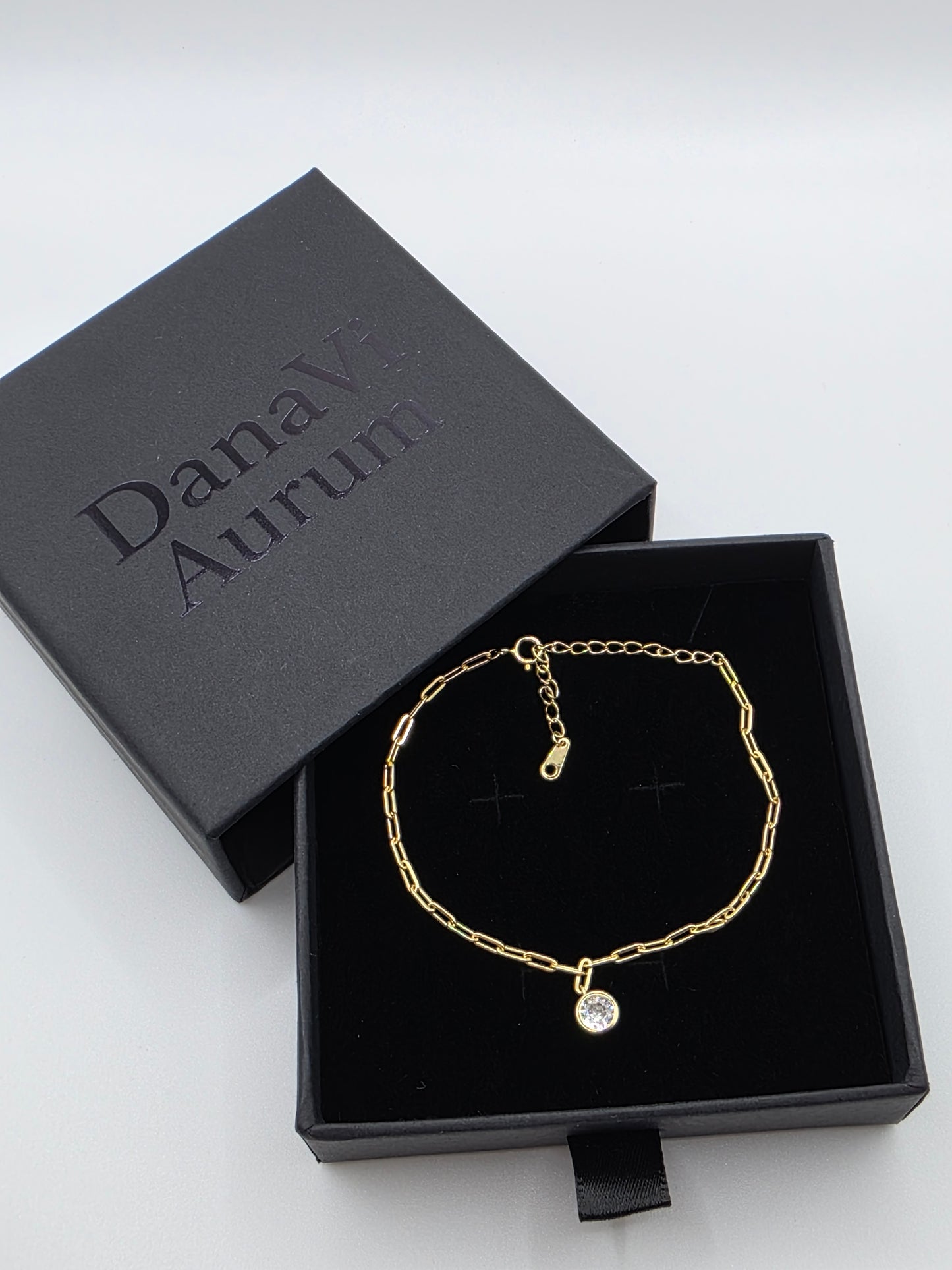Gold bracelet in a black jewelry box with 'Danavi Aurum' branding on a white background