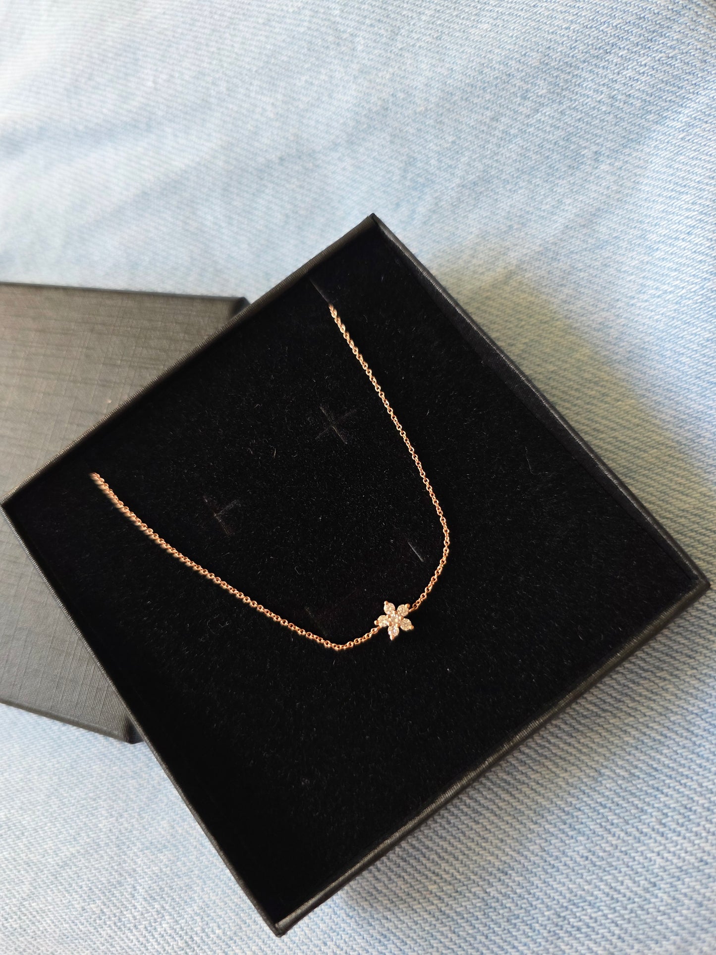 14k Rose gold bracelet with a starflower pendant on a black jewelry box. Danavi aurum uk jewellery