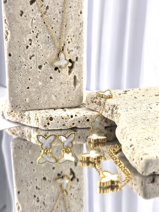 Gold butterfly-shaped necklace on a textured stone surface danavi aurum