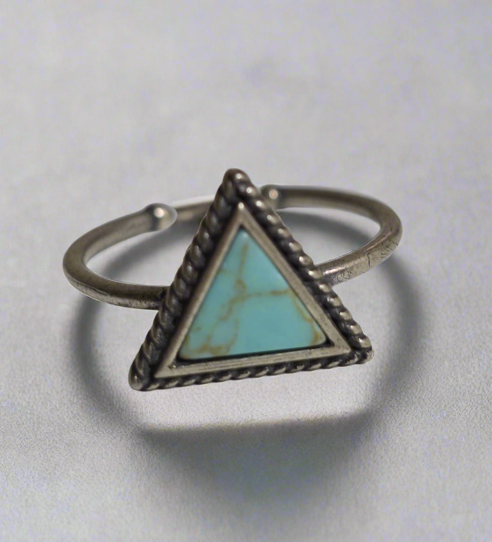 Silver ring with a turquoise triangle stone on a light gray background