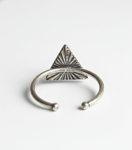 Silver ring with a triangular design on a gray background