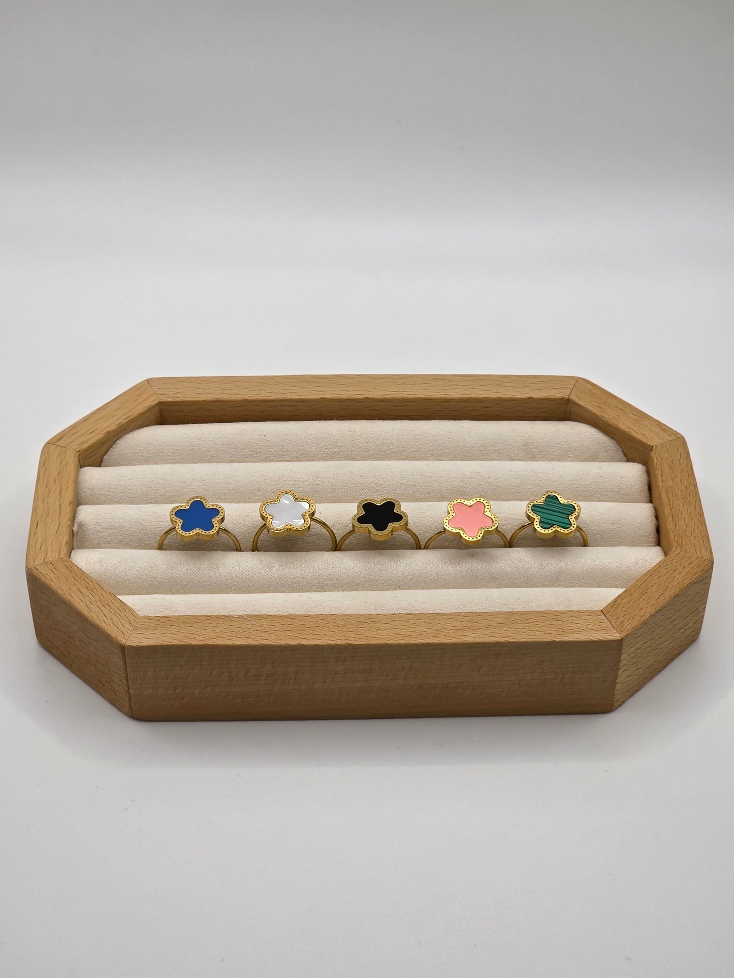 Wooden jewelry display with colorful rings on a white background danavi aurum