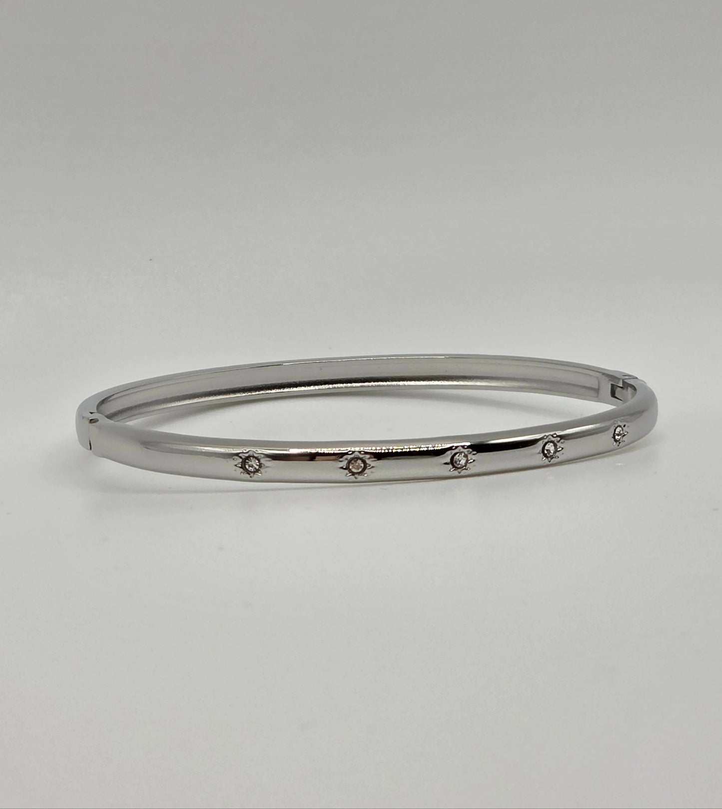 Silver bangle with small stones on a light gray background