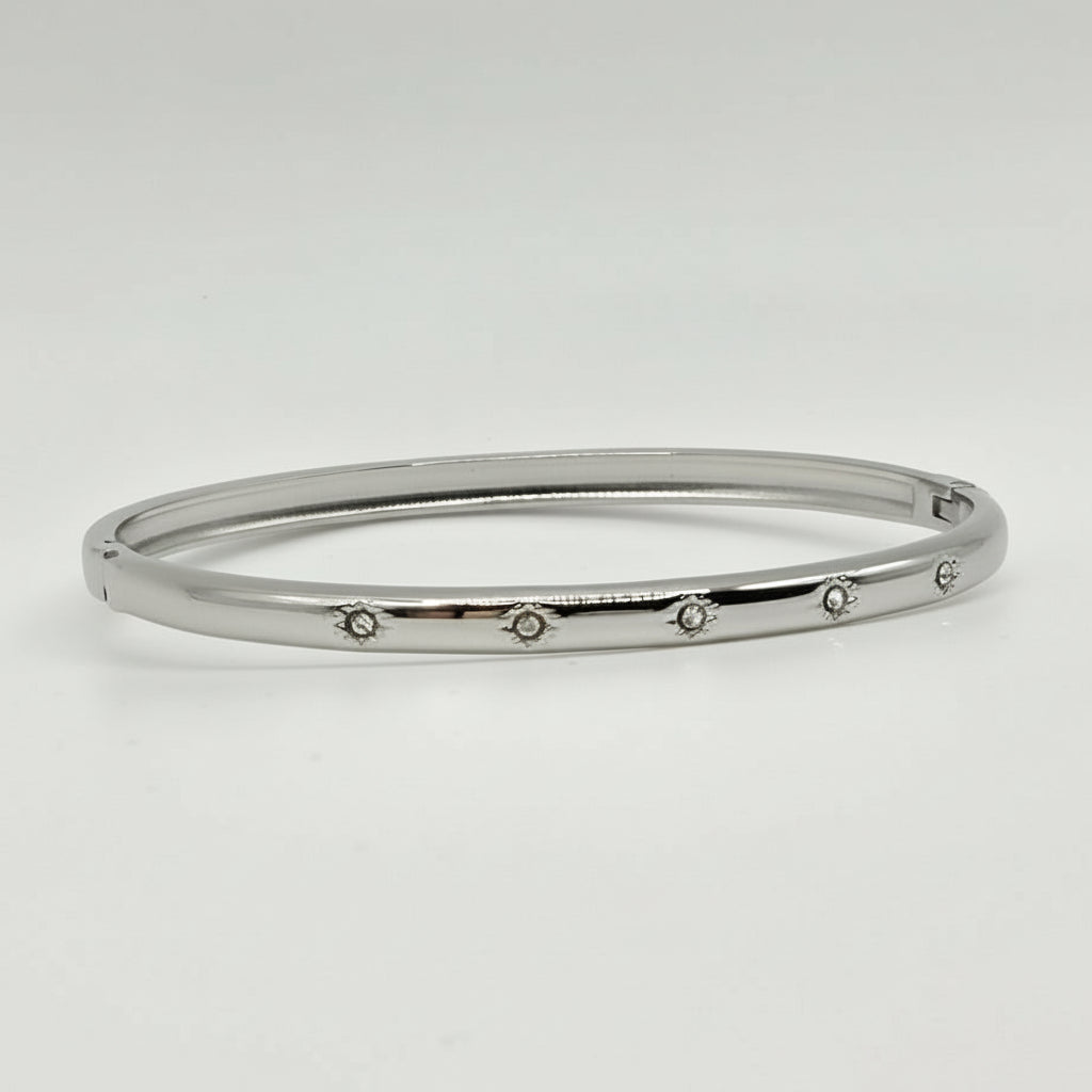 Silver bangle with small stones on a light gray background