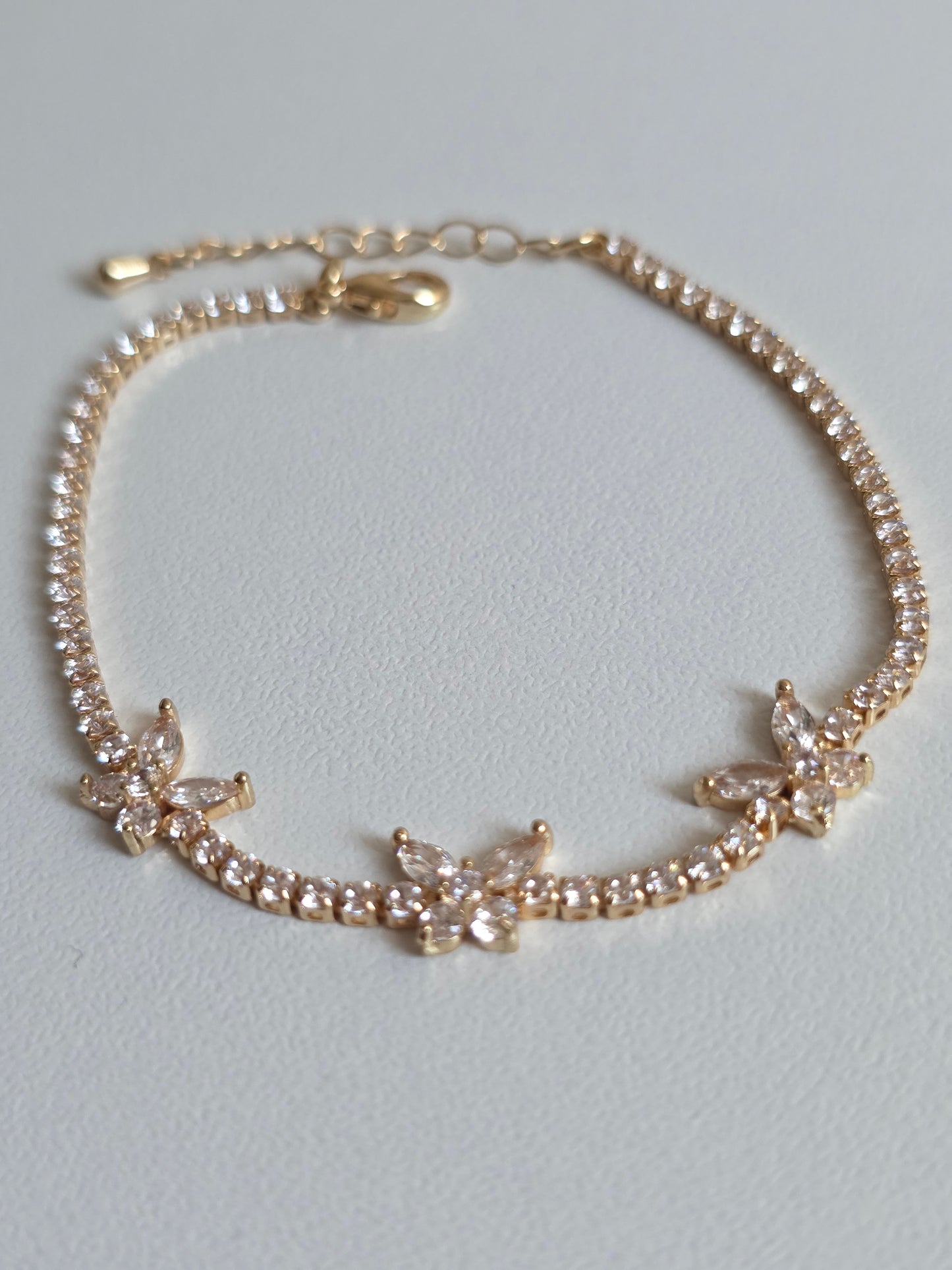 Gold bracelet with diamond butterfly accents on a light gray background UK based