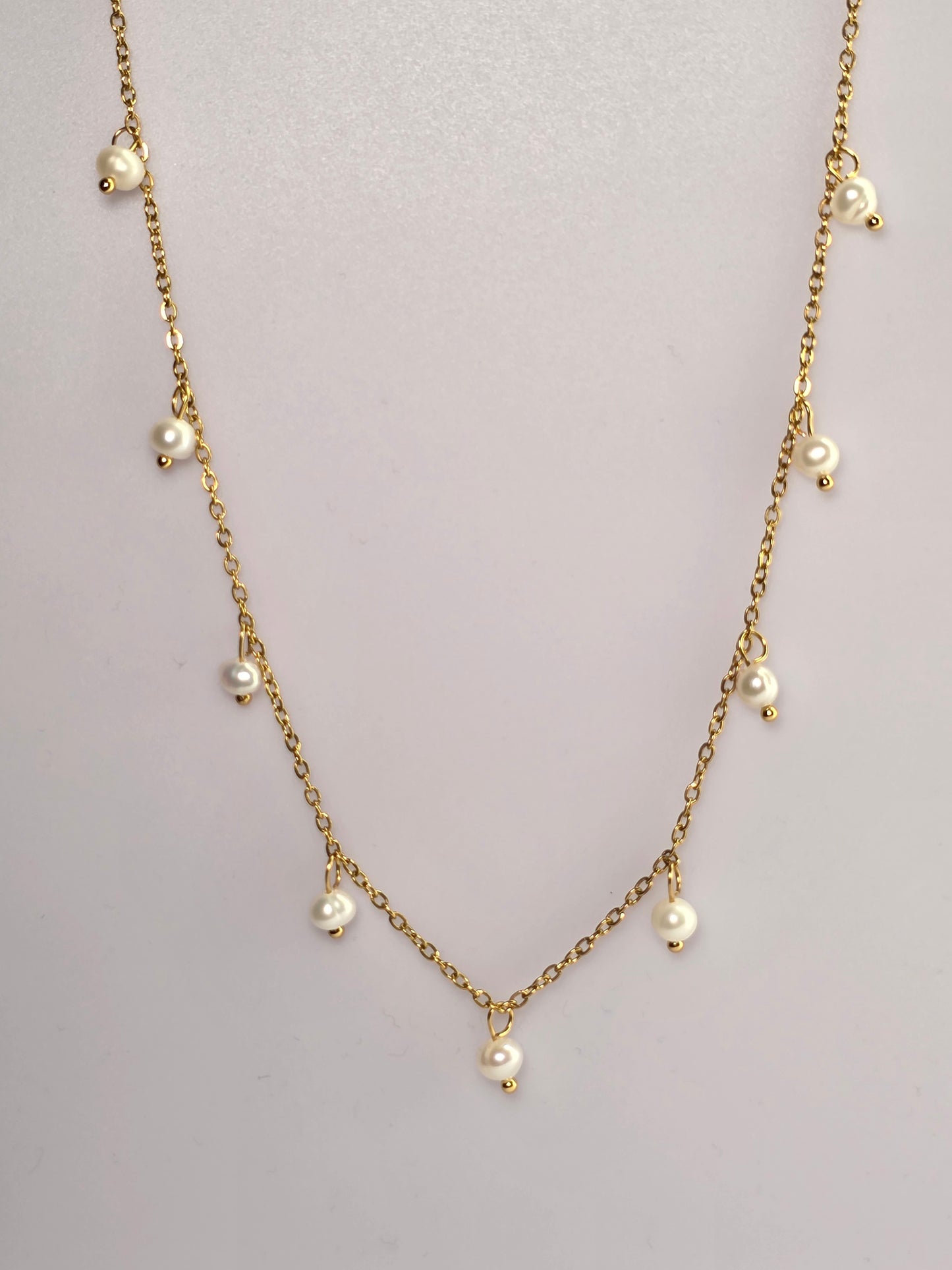 Gold chain necklace with pearls on a light gray background danavi aurum