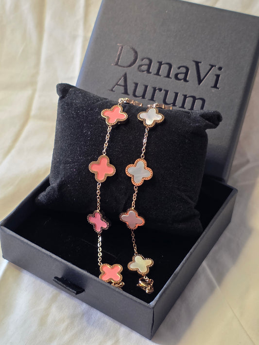 Bracelet with pink clover-shaped charms on a black cushion inside a DanaVi Aurum box.