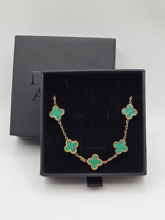 Bracelet with green clover-shaped charms in a black box on a light gray background danavi aurum