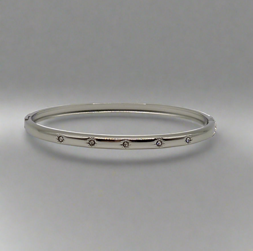 Silver bangle with small stones on a gray background