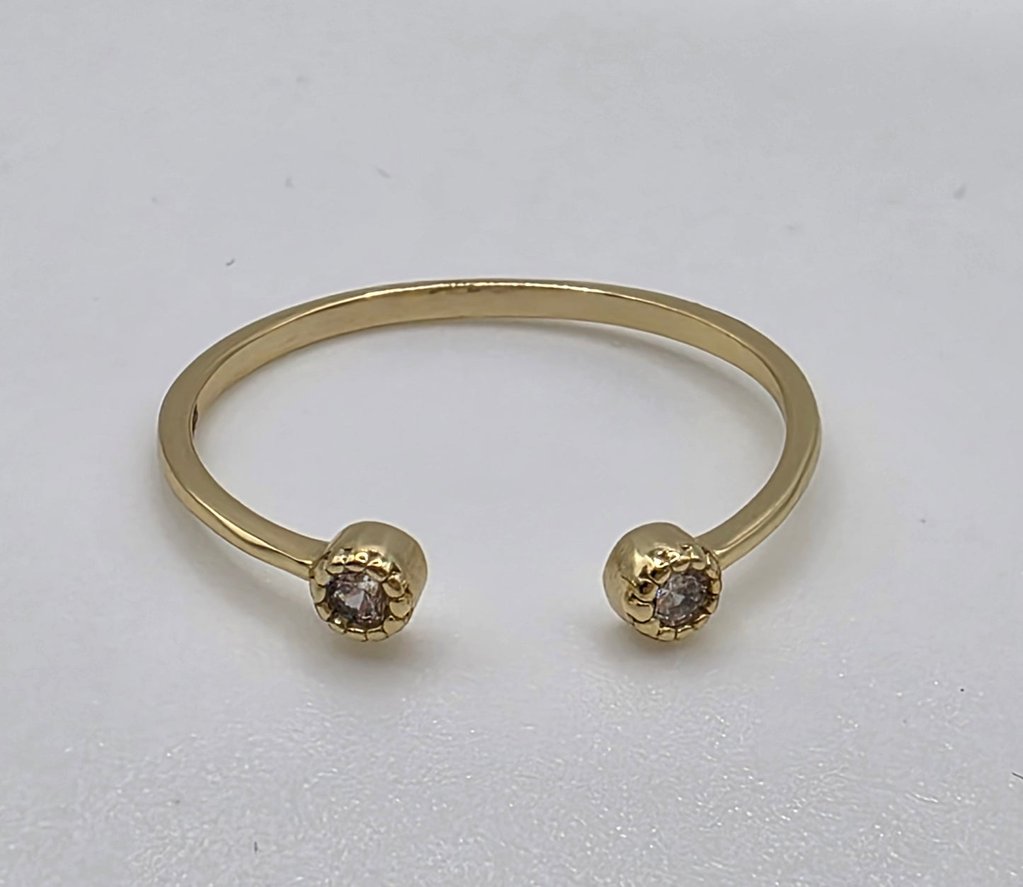 Gold ring with two round gemstones on a light gray background