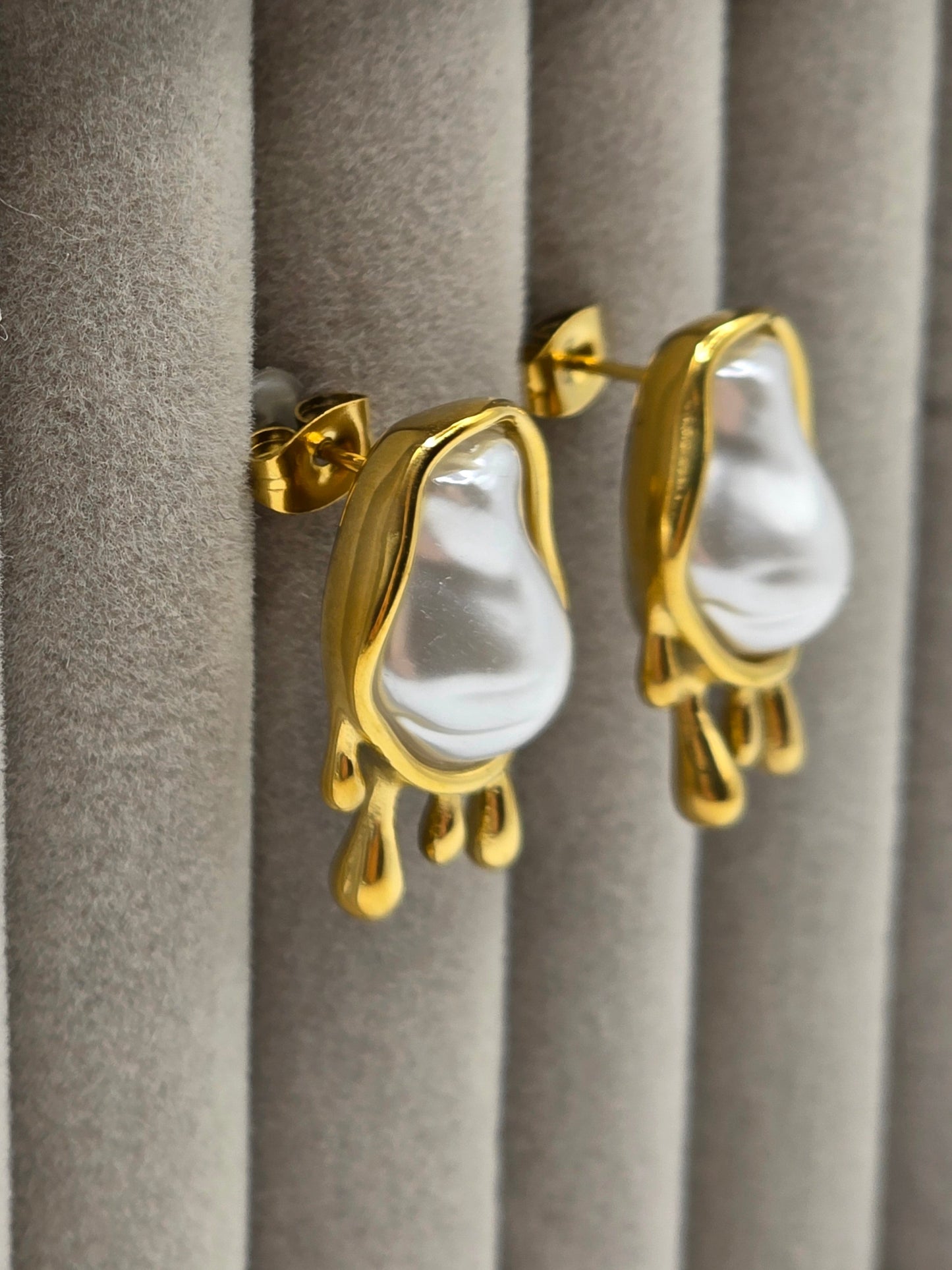 Gold earrings with white stones on a gray surface danavi aurum