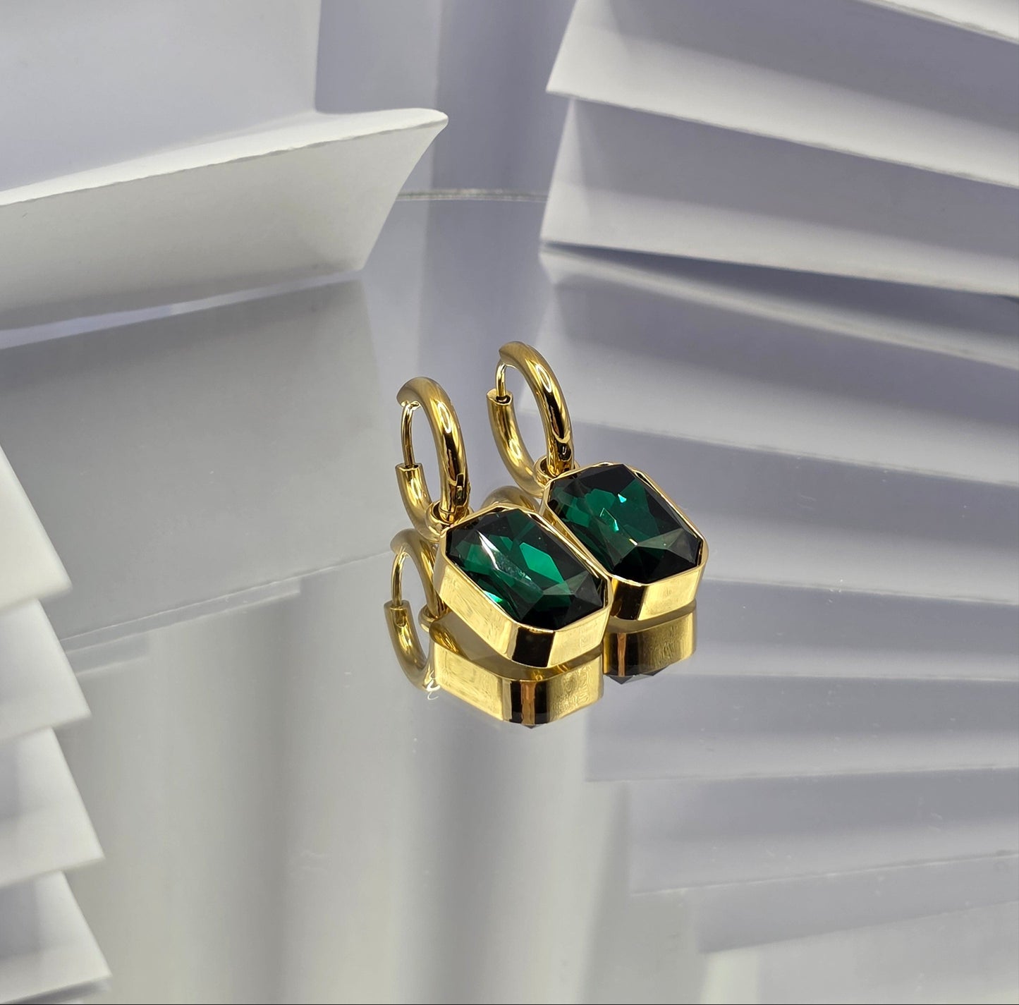 Gold ring with green gemstones on a white geometric background danavi aurum