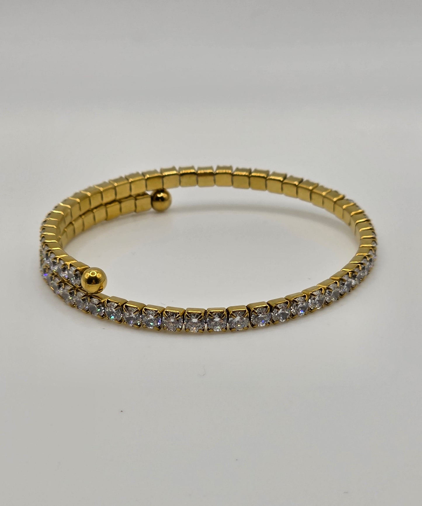 Gold bracelet with embedded stones on a light gray background danavi aurum