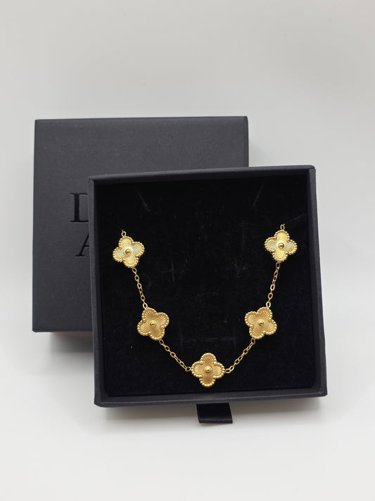 Gold bracelet with floral designs in a black jewelry box on a light gray background danavi aurum