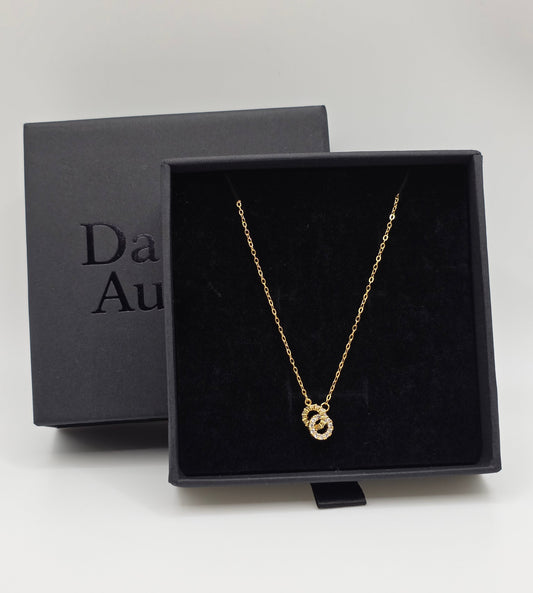 Gold necklace in a black box with 'Da naVi Aurum' branding on a white background