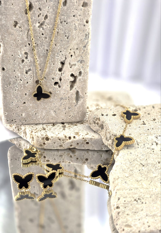 Butterfly-shaped necklace with black details on a stone surface danavi aurum