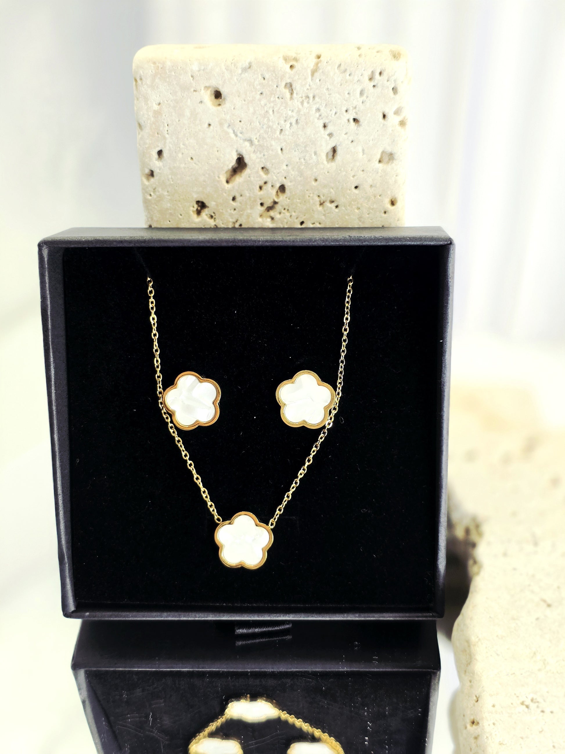Gold necklace and earrings set in a black box with a white background