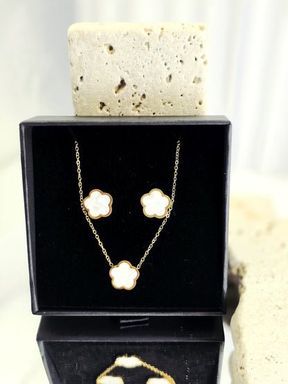 Gold necklace and earrings set in a black box with a white background