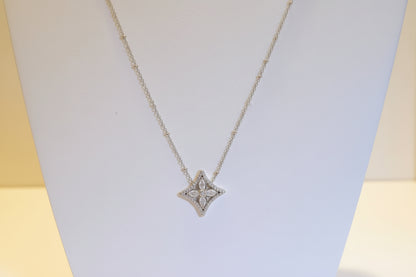 Star-shaped diamond pendant on a gold chain against a light background