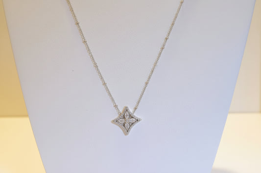 Star-shaped diamond pendant on a gold chain against a light background