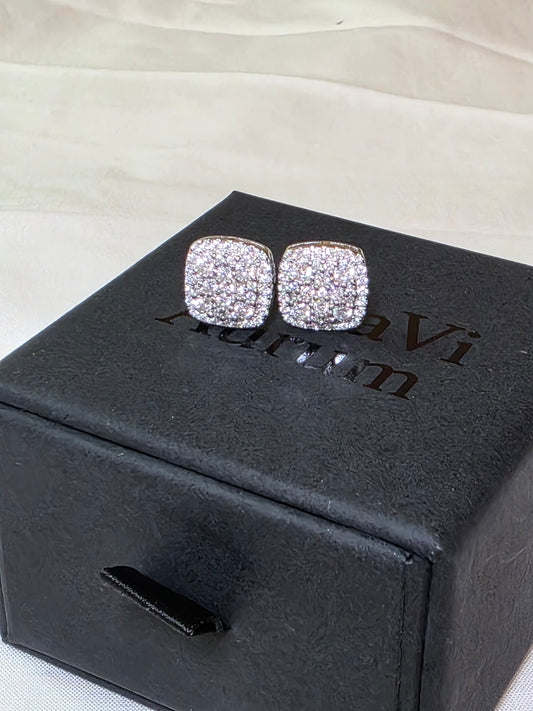 Silver glittery earrings on a black box with 'Danavi Aurum' branding.