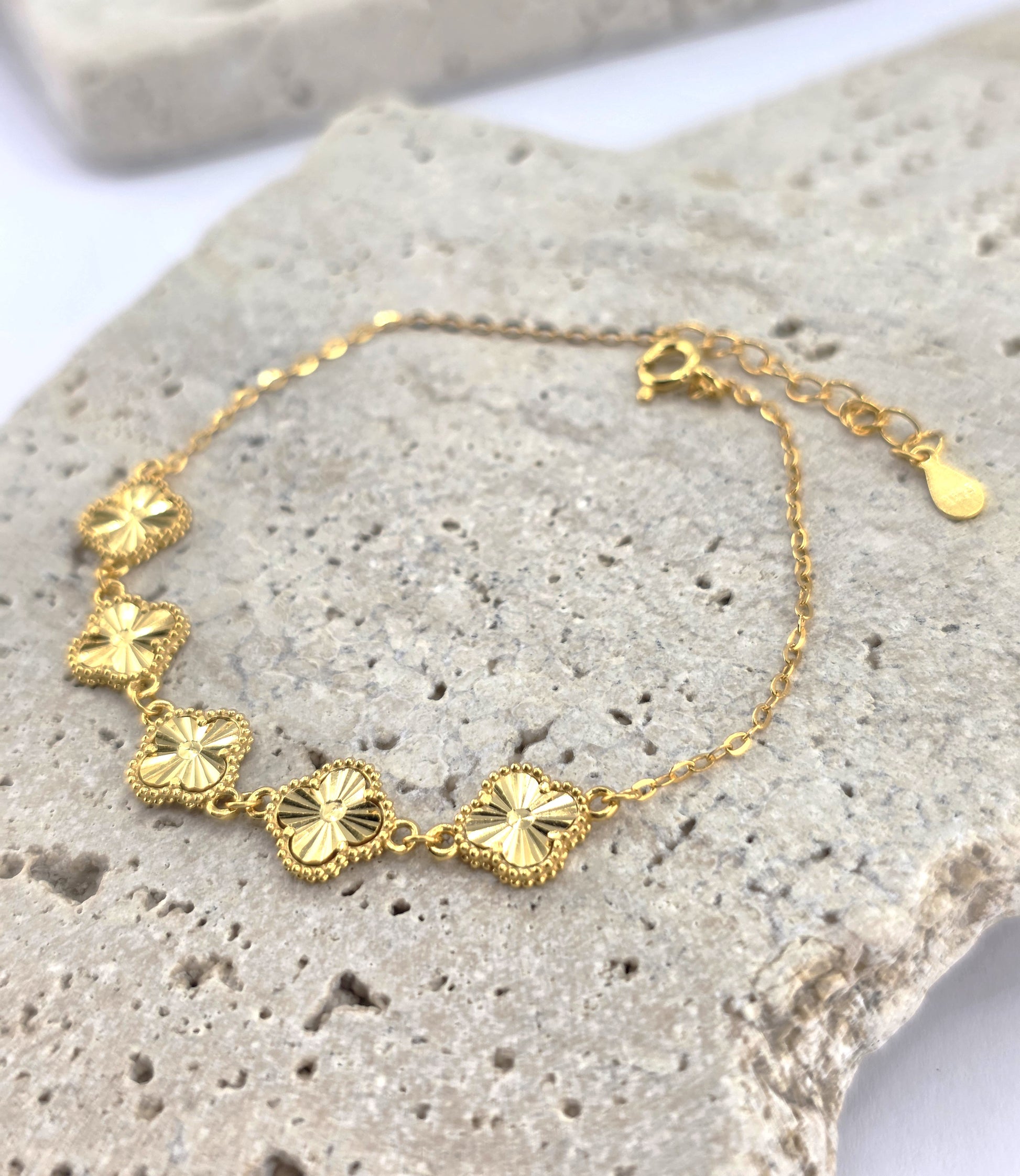 Gold bracelet with floral designs on a textured stone surface danavi aurum