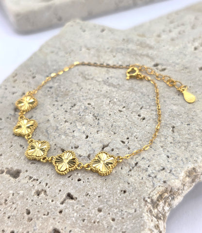 Gold bracelet with floral designs on a textured stone surface danavi aurum