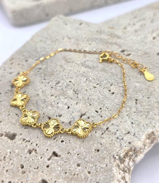 Gold bracelet with floral designs on a textured stone surface danavi aurum