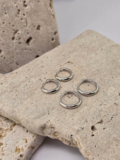 Silver hoop earrings on a textured stone surface