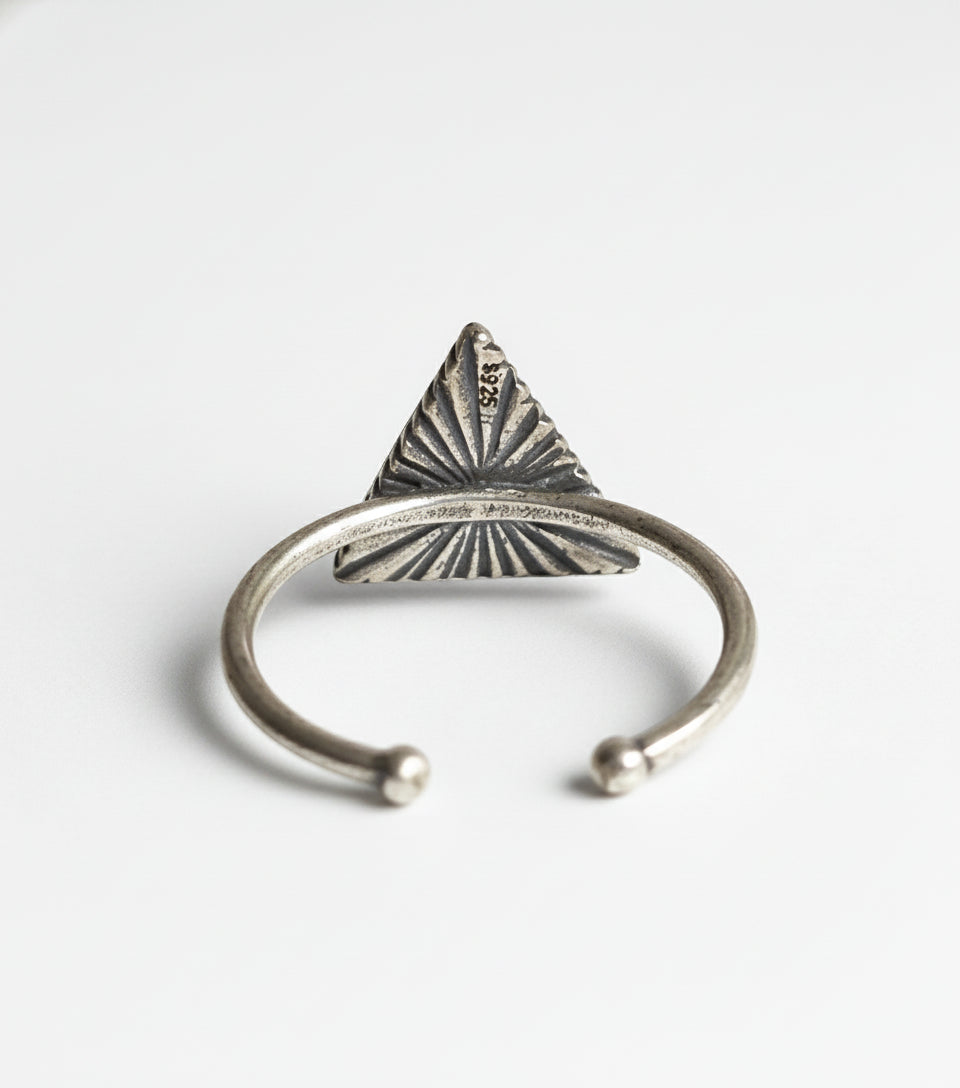 Silver ring with a triangular design on a gray background