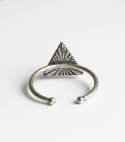 Silver ring with a triangular design on a gray background