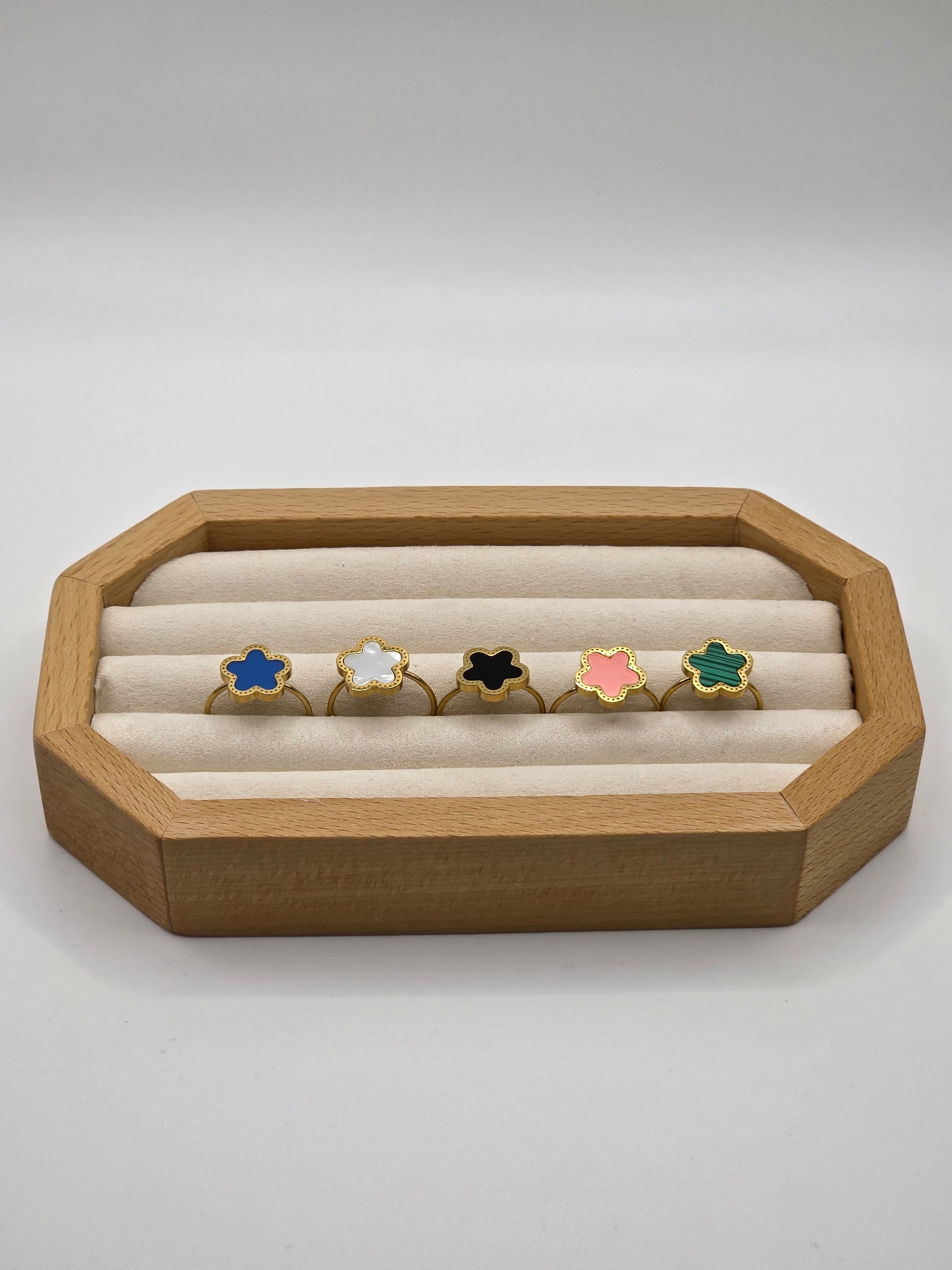 Wooden jewelry display with colorful rings on a white background danavi aurum