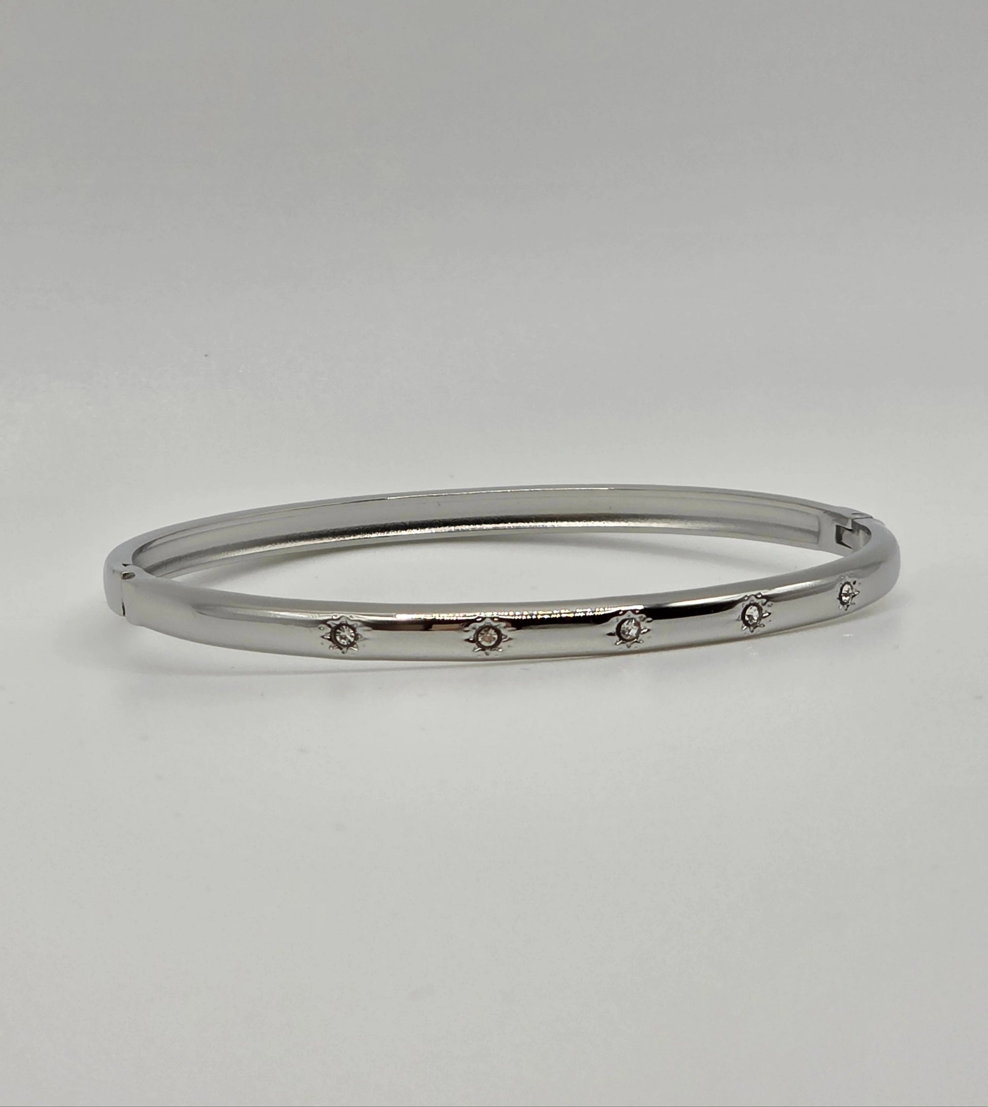 Silver bangle with small stones on a light gray background