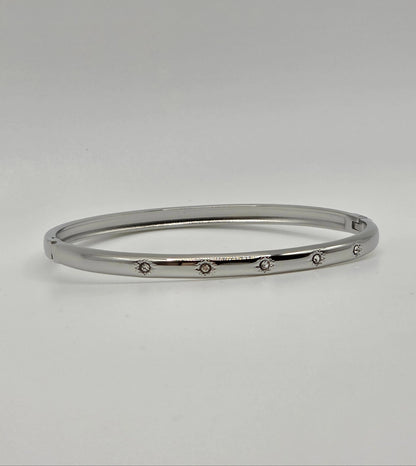 Silver bangle with small stones on a light gray background