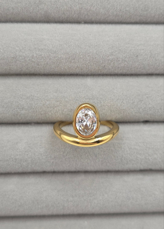 Gold ring with a clear gemstone on a gray textured background