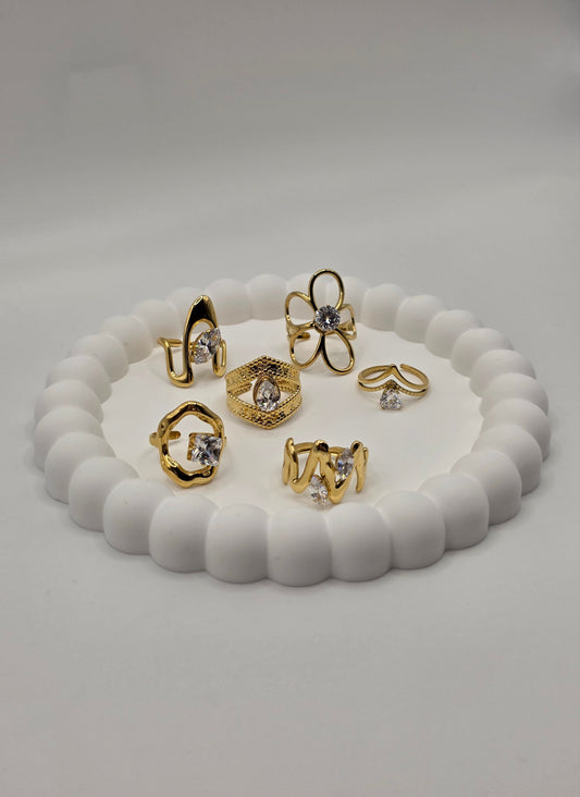 Set of gold and silver rings on a white shell-shaped stand against a light gray background Danavi Aurum