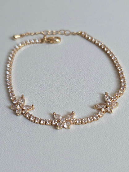 Gold bracelet with diamond butterfly accents on a light gray background UK based
