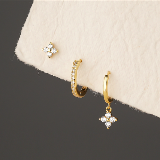 Gold earrings with diamond-like stones on a beige fabric background danavi