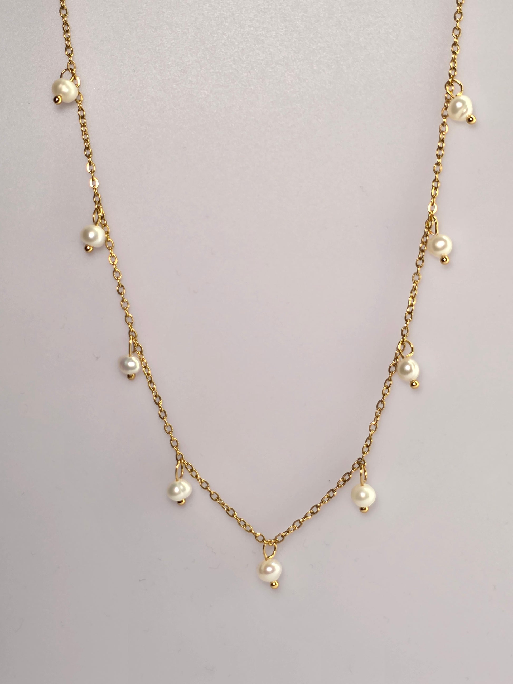 Gold chain necklace with pearls on a light gray background danavi aurum