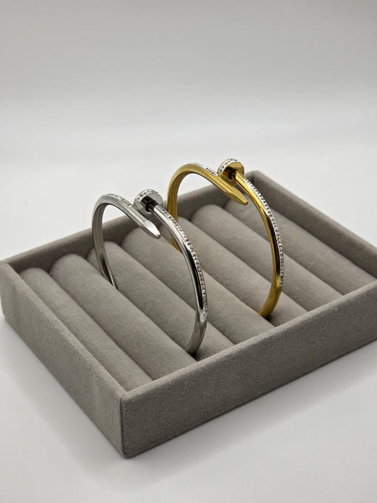 Two gold and silver bangles in a gray jewelry box on a light gray danavi aurumbackground