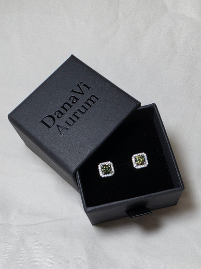 Square earrings with emerald like gemstones in a black jewelry box on a light gray background