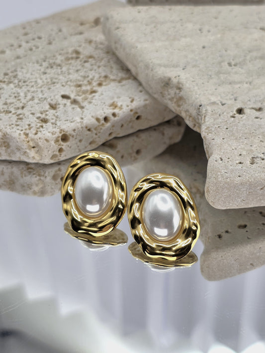 Gold earrings with pearl-like centers on a stone surface danavi Aurum