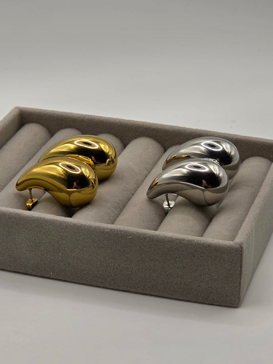 Pair of gold and silver danavi aurum earrings in a display case on a white background