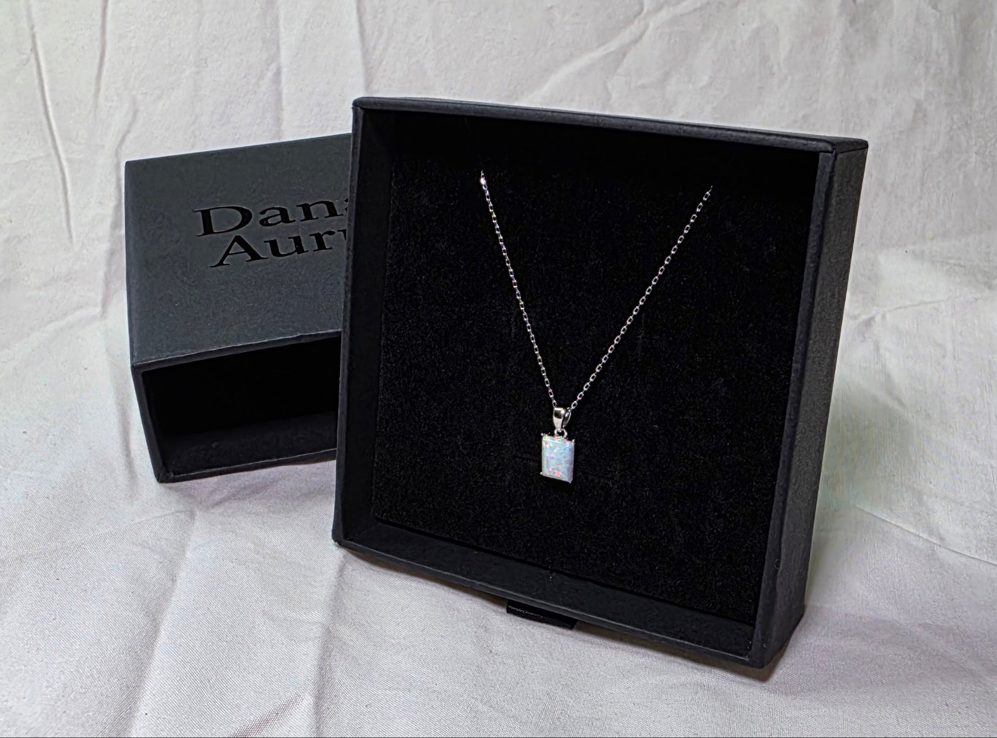 Necklace with a pendant in a Danavi Aurum black box on a white fabric background