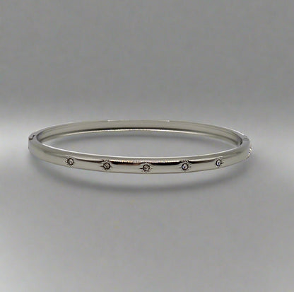 Silver bangle with small stones on a gray background