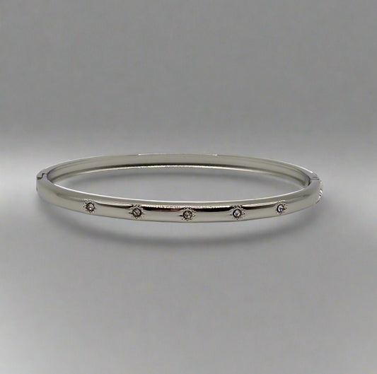 Silver bangle with small stones on a gray background