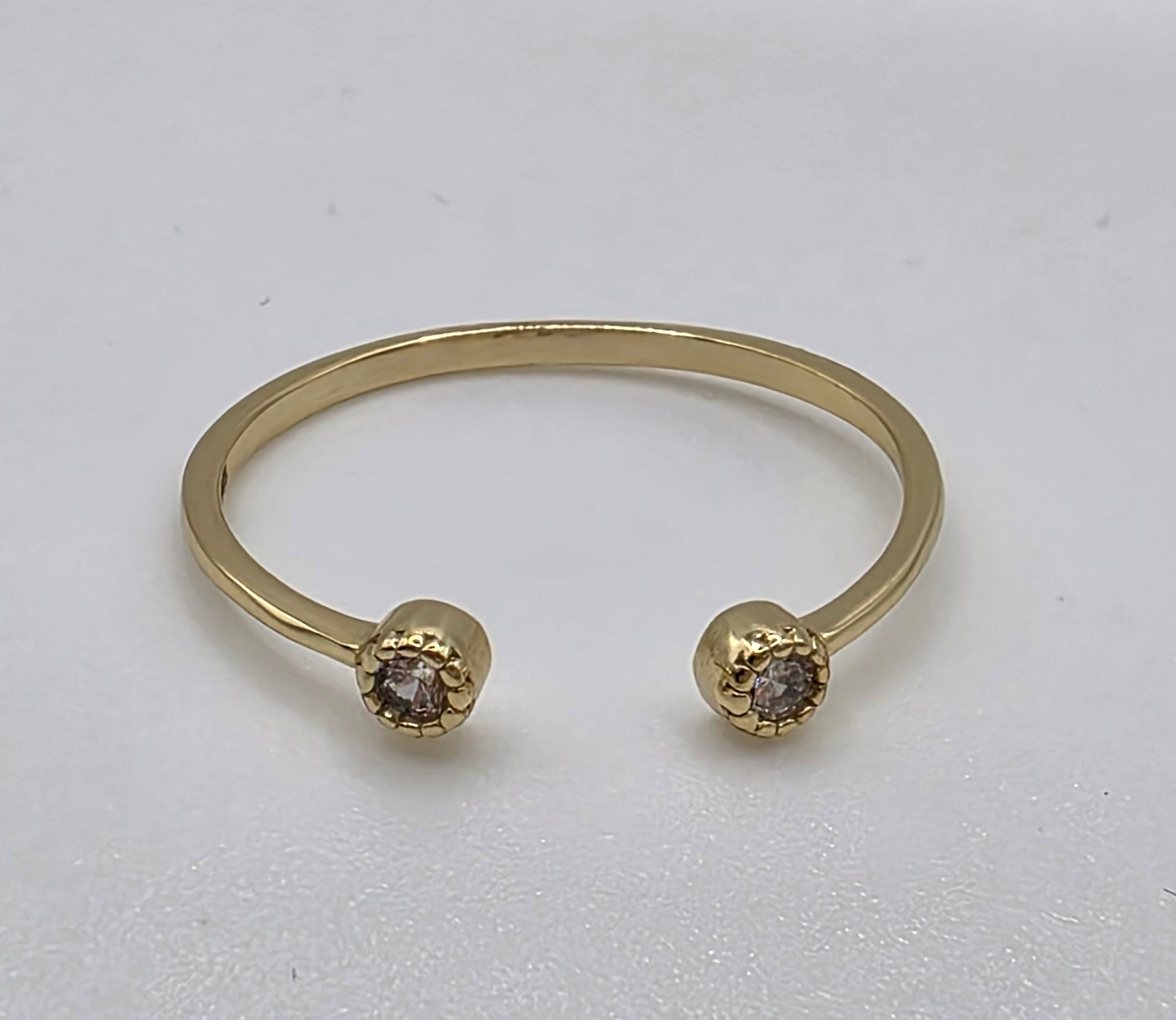 Gold ring with two round gemstones on a light gray background