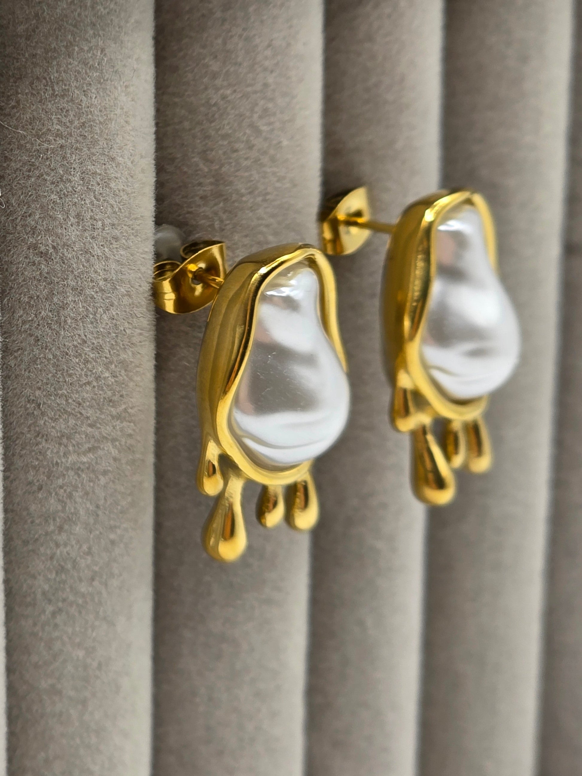 Gold earrings with white stones on a gray surface danavi aurum