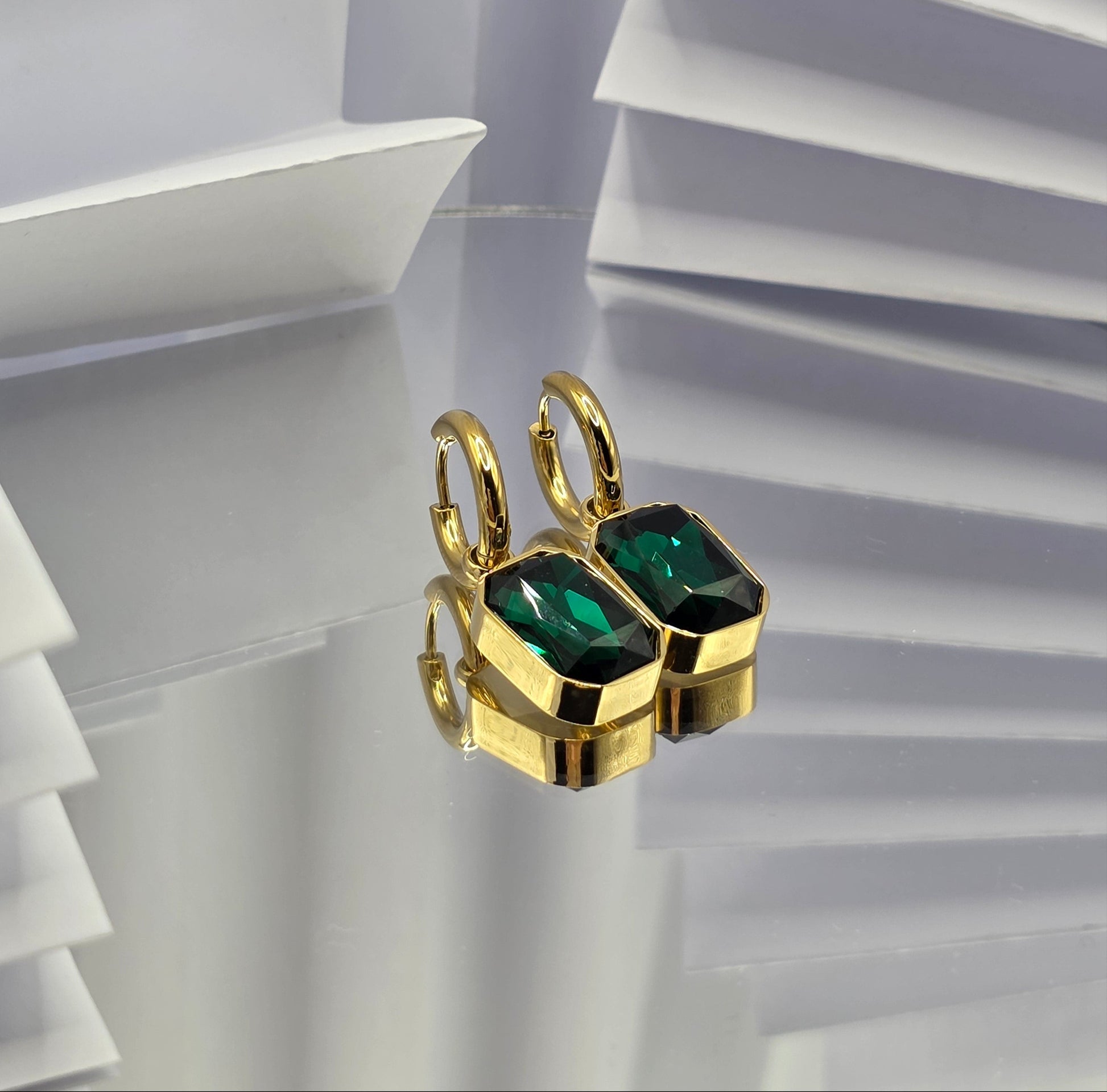Gold ring with green gemstones on a white geometric background danavi aurum